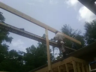 Carpenter setting a ridge beam over a new addition frame — Ice Dam Removal by Roofing Brothers in Lumberton
