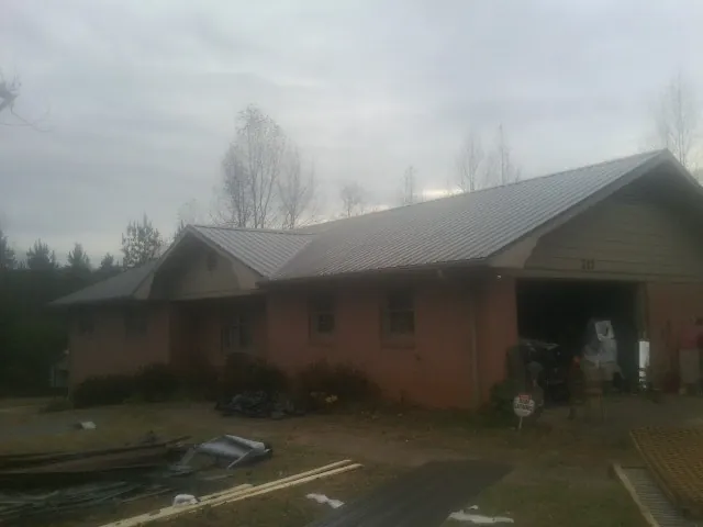 Gray metal roof on a stucco house with an attached garage in Lumberton