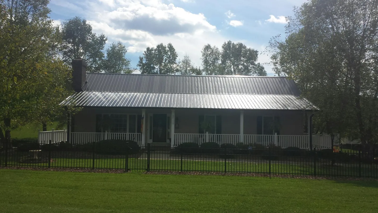 Gray metal roof on a brick ranch with a full width front porch — Gutter Guard Installation work by our crew in Lumberton